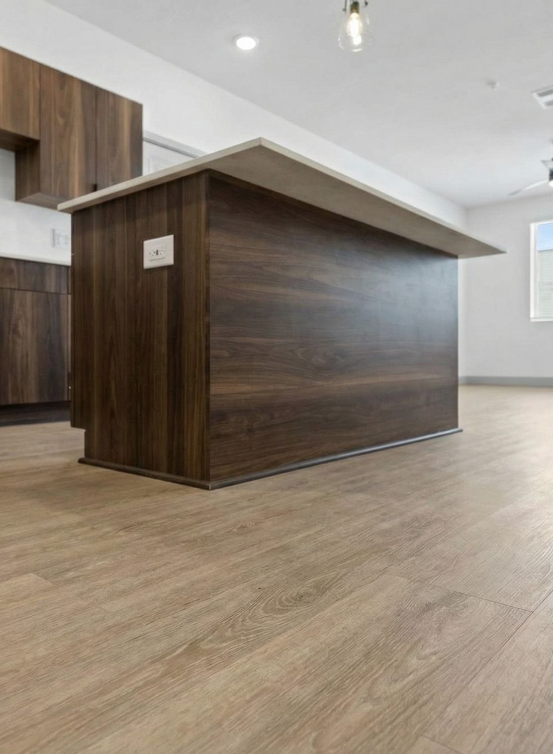 Modern kitchen with wood cabinets, large island, and light wood flooring in a bright, open space.